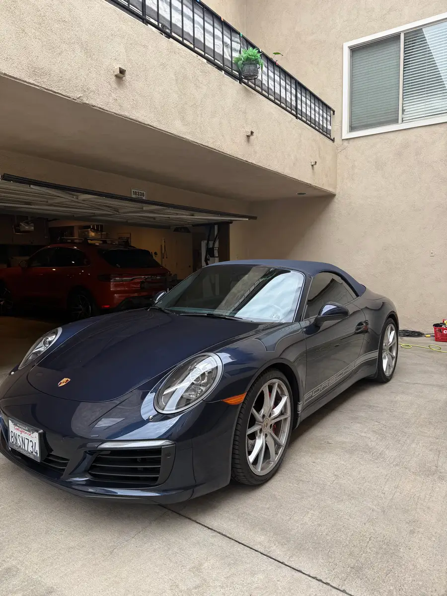 Dark blue Porsche 911 in front of an open garage, a sunshade on the windshield