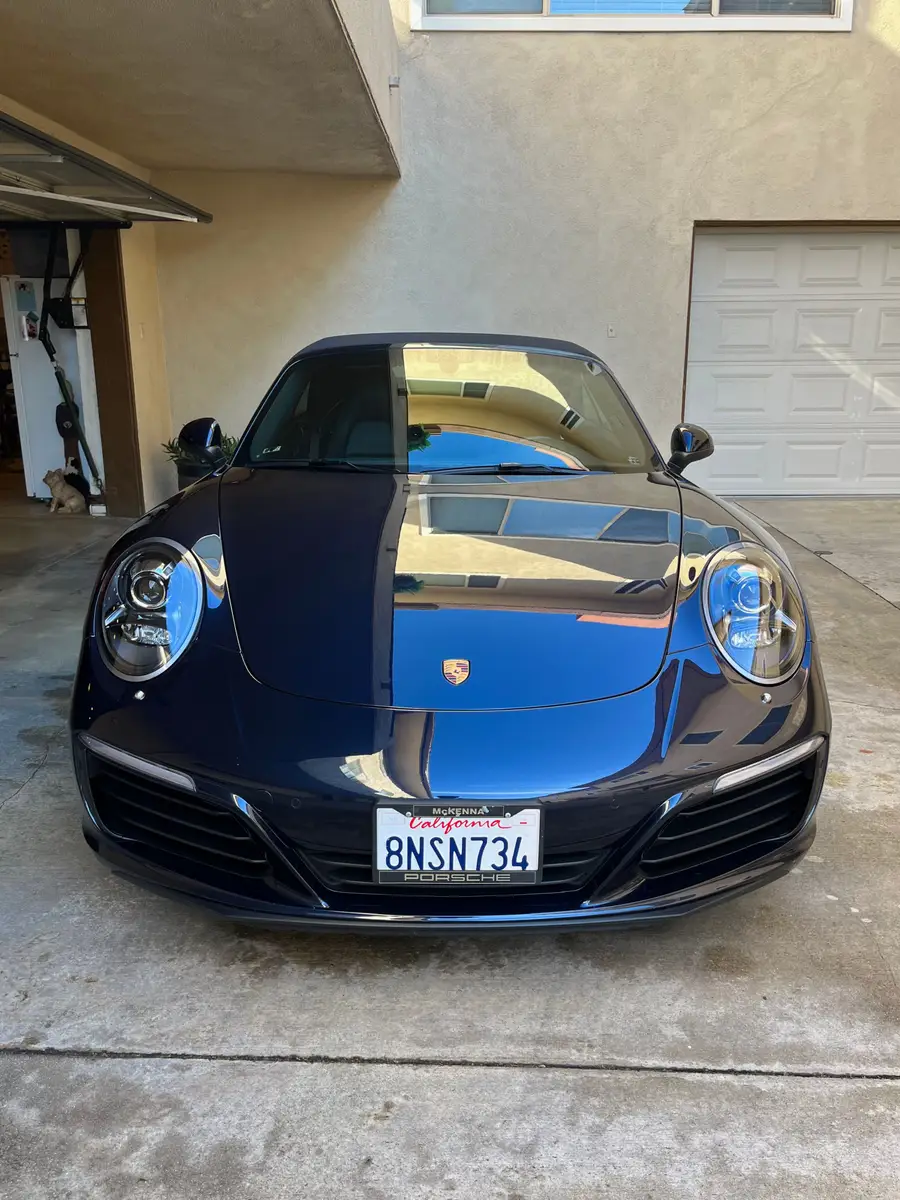 Dark blue Porsche 911, head-on in a garage doorway, paint reflecting after a detail
