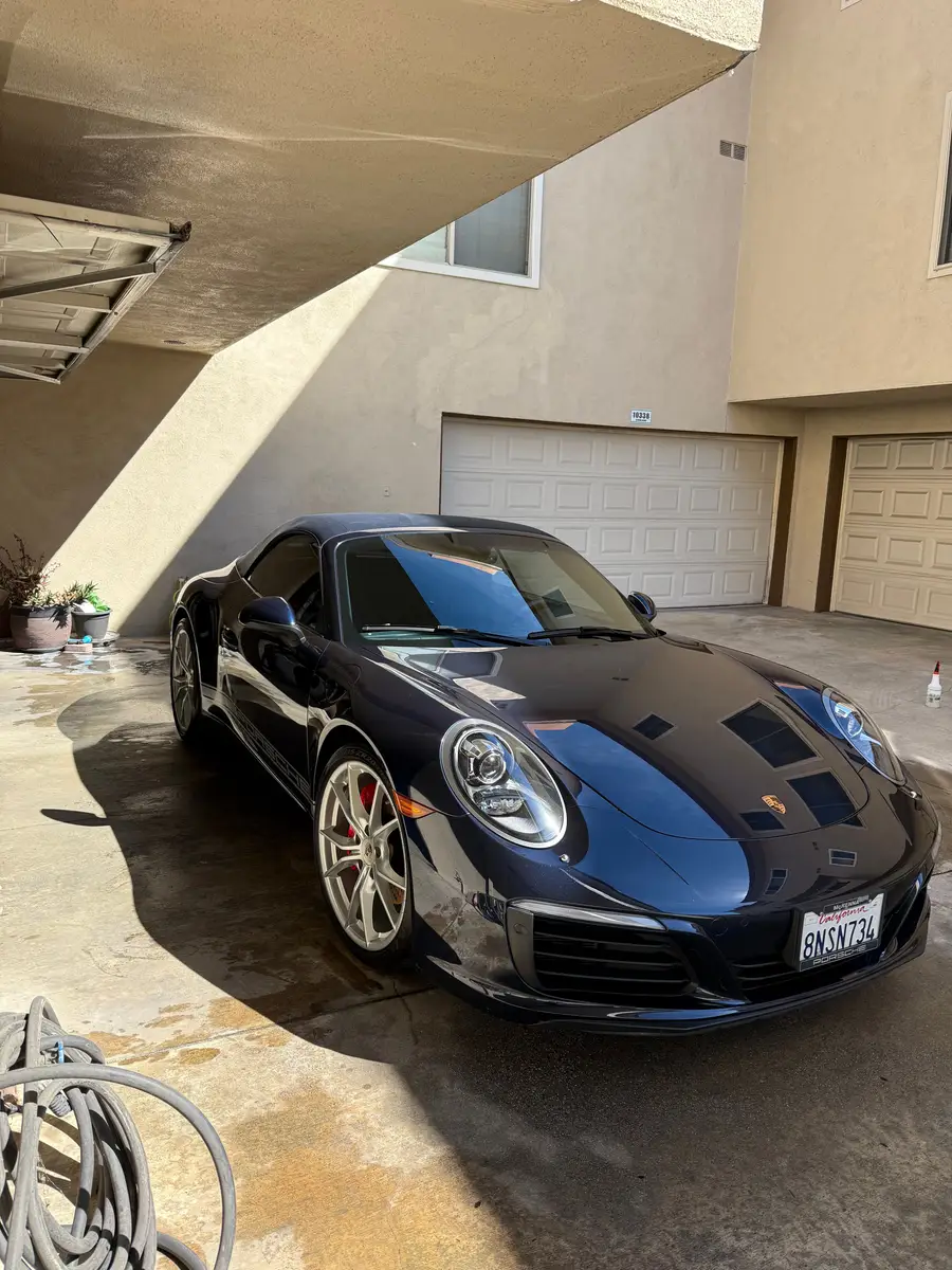 Dark blue Porsche 911 after a wash, the driveway still wet