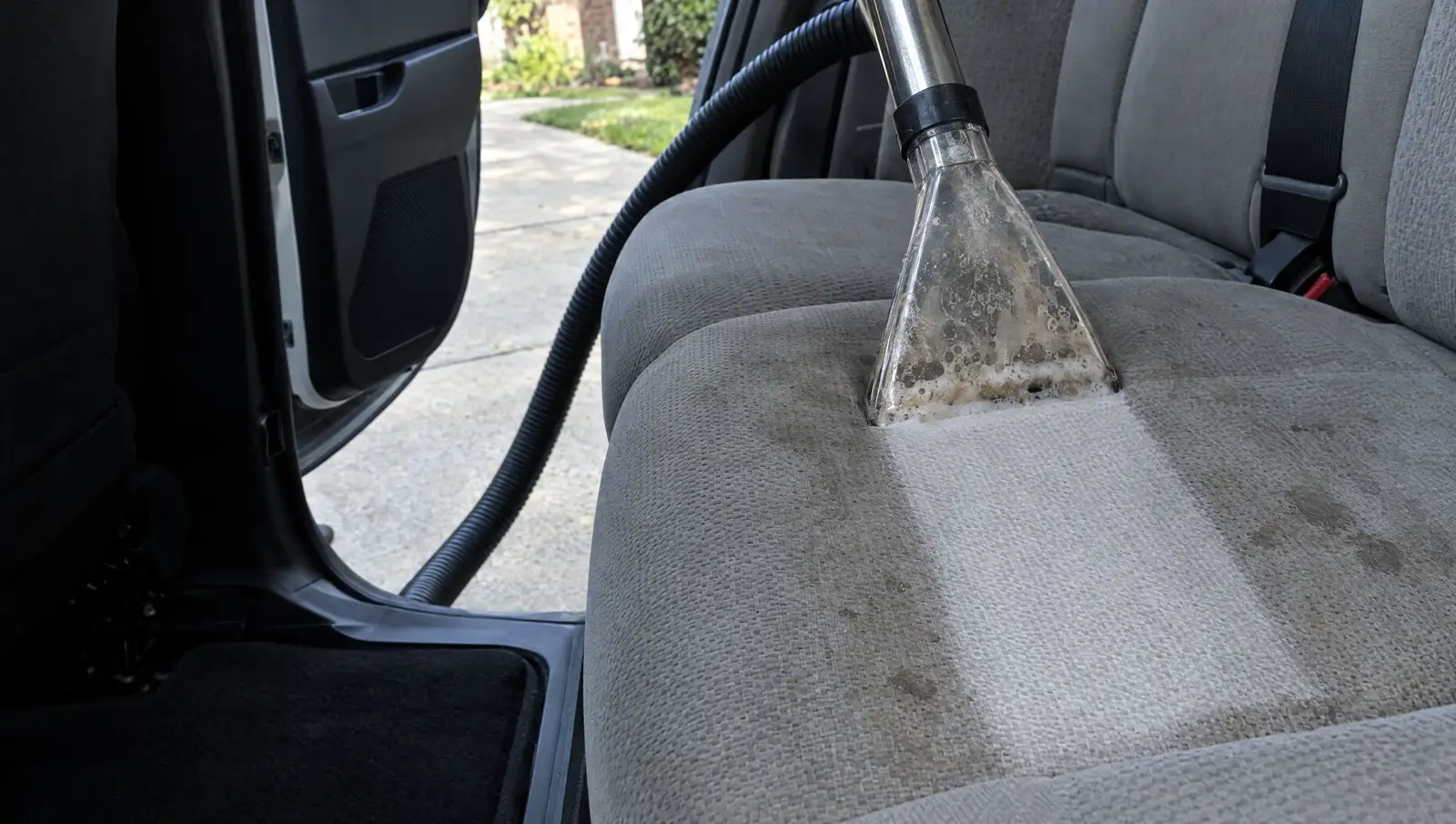 Hot water extractor wand pulling a clean stripe through a stained cloth rear seat