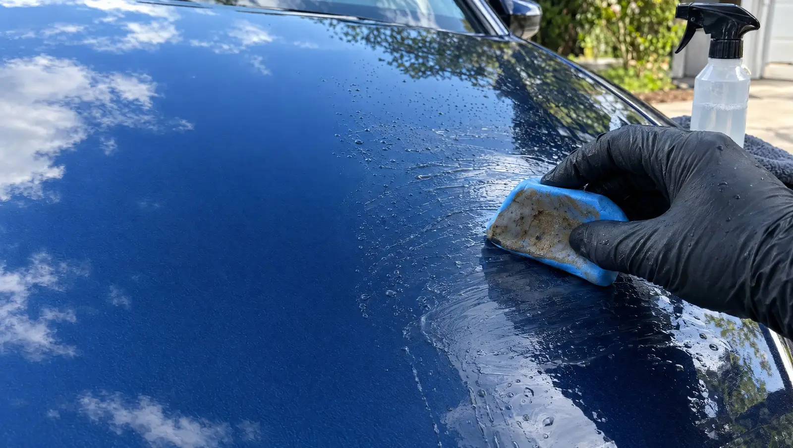 Clay bar gliding over a lubricated blue hood, contamination picked up on the clay