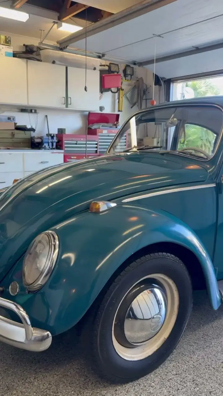 Classic teal Volkswagen Beetle detailed inside a home garage