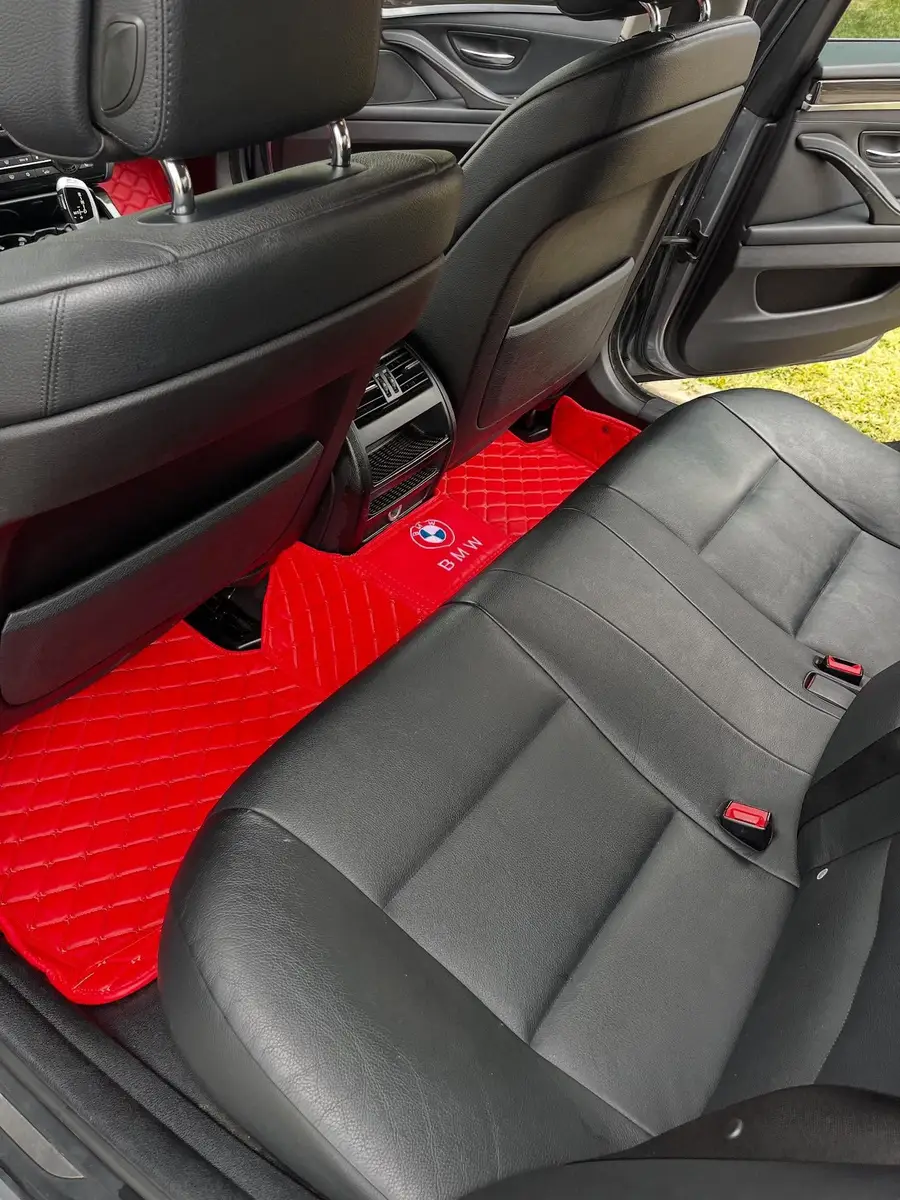 Black leather seats and red floor mats in a BMW after an interior detail