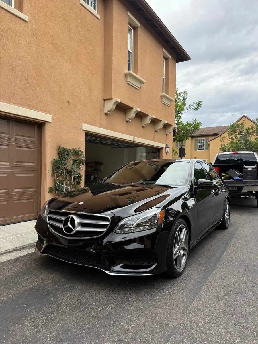 Black Mercedes-Benz E-Class after detailing, parked in front of a garage