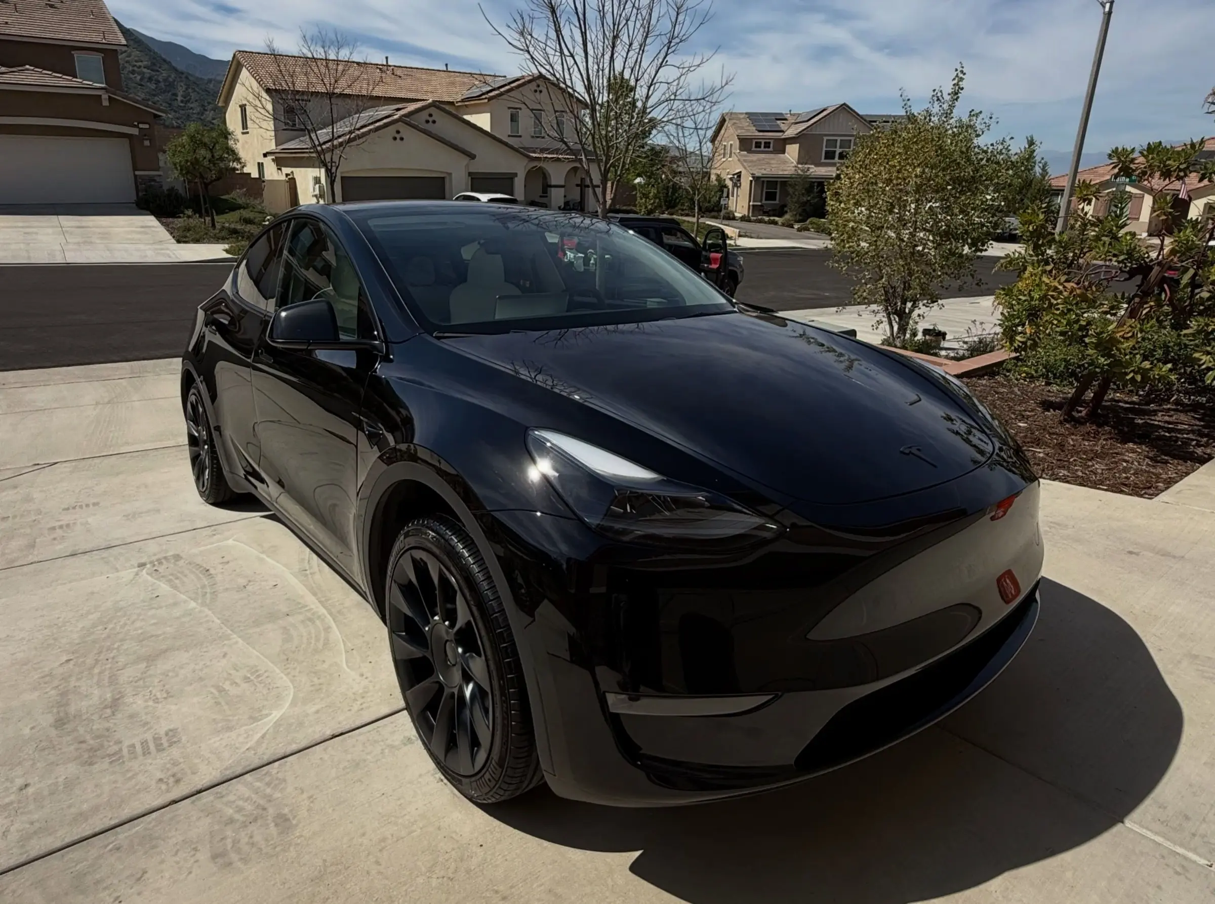 Black Tesla Model Y after a mobile detail, glossy in a customer's driveway