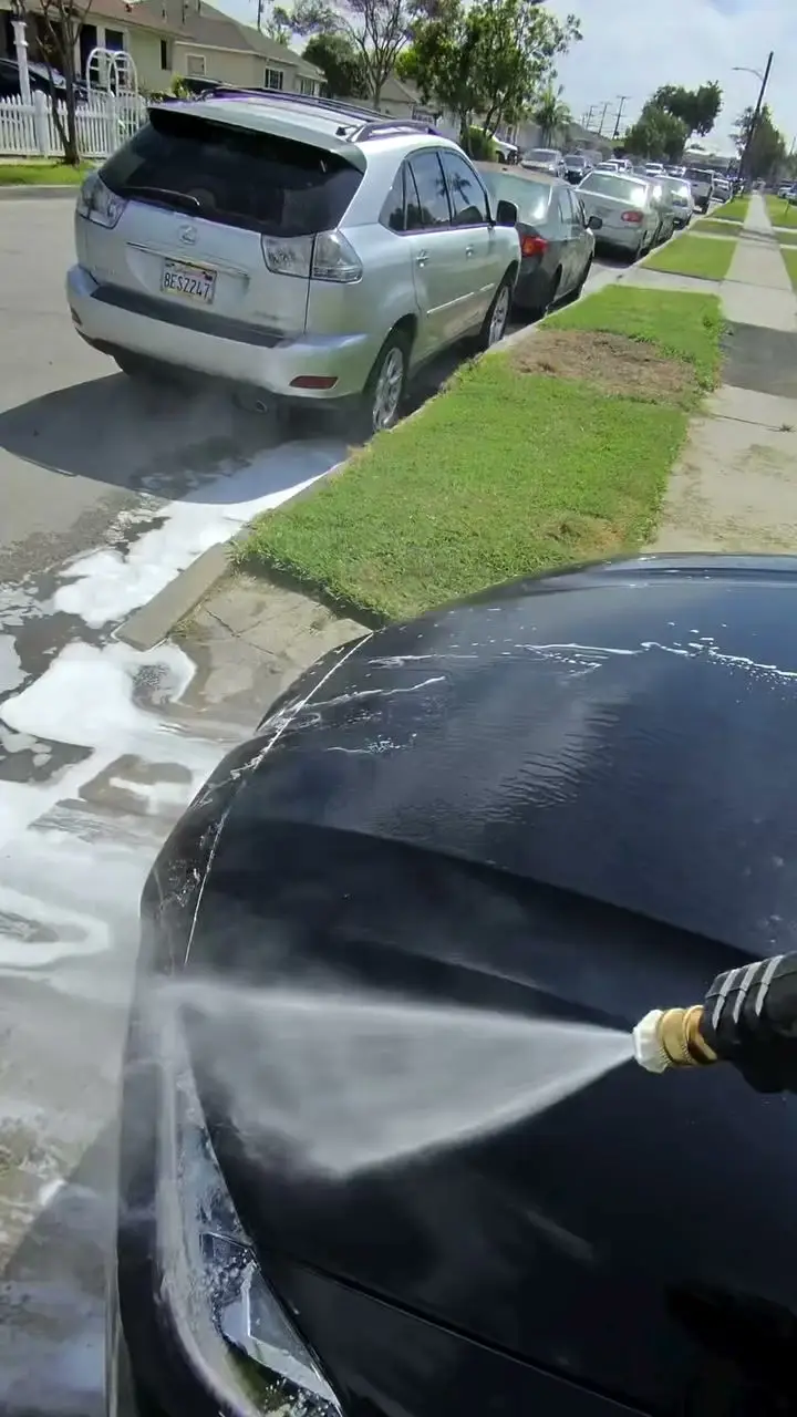 Rinsing foam off a car with a pressure washer in the street