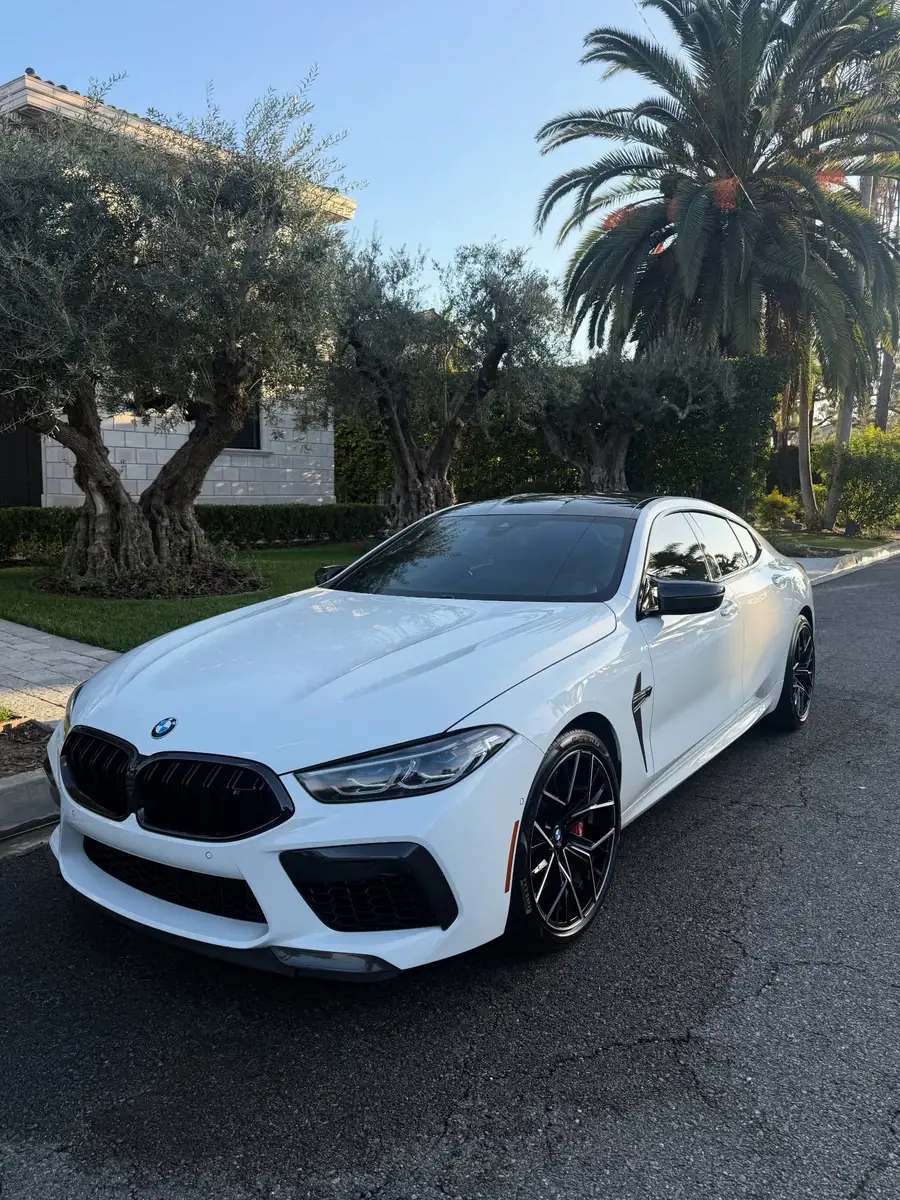 White BMW M8 Competition after detailing, parked on a residential street under palm trees