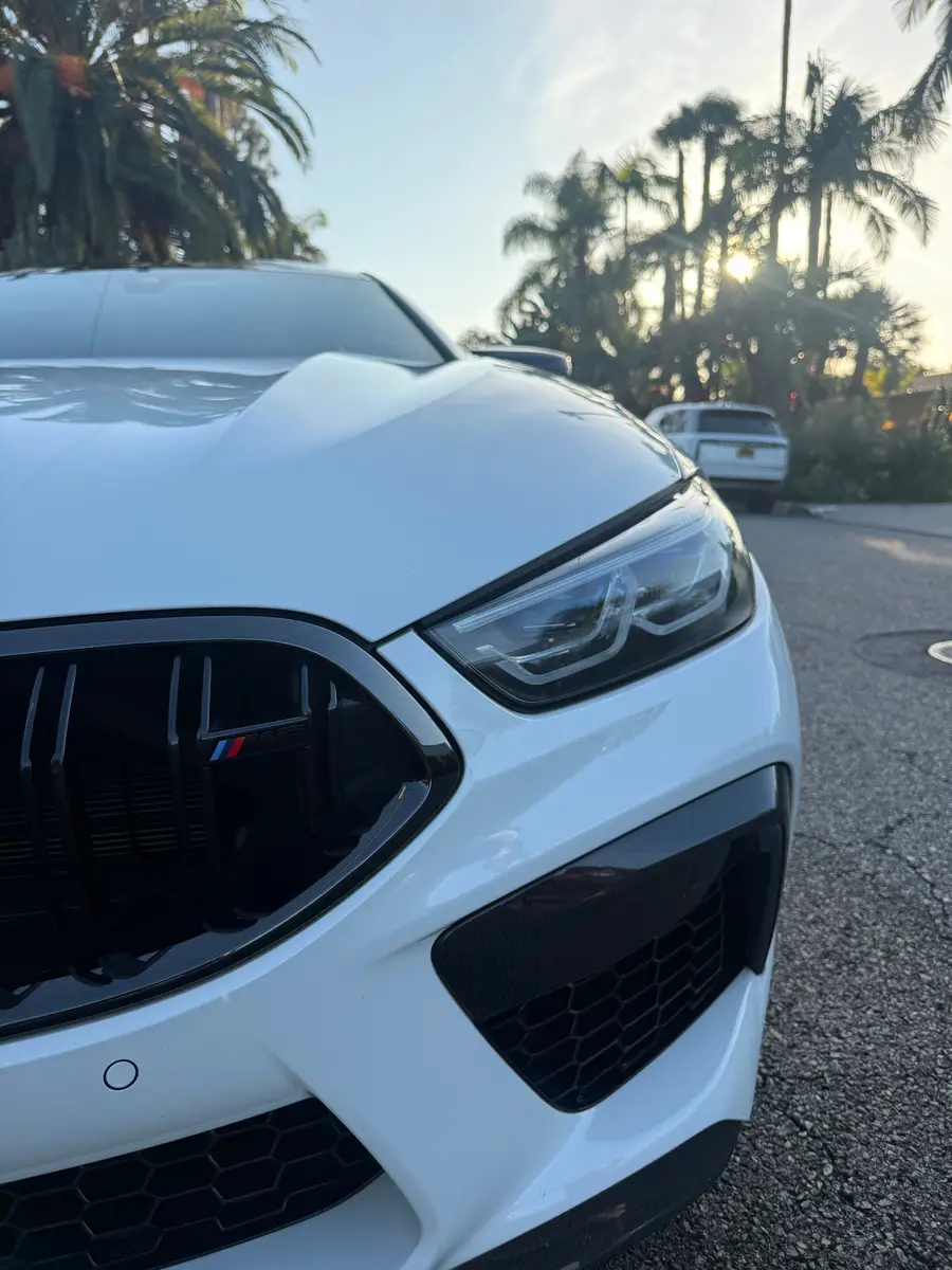 Close-up of a white BMW M8 headlight and grille after detailing
