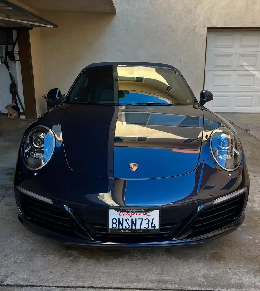 Dark blue Porsche 911 Carrera, freshly detailed, in front of a garage