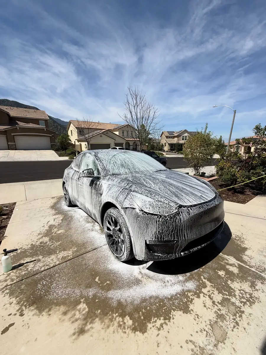 Tesla Model Y covered in foam during a mobile wash in the driveway