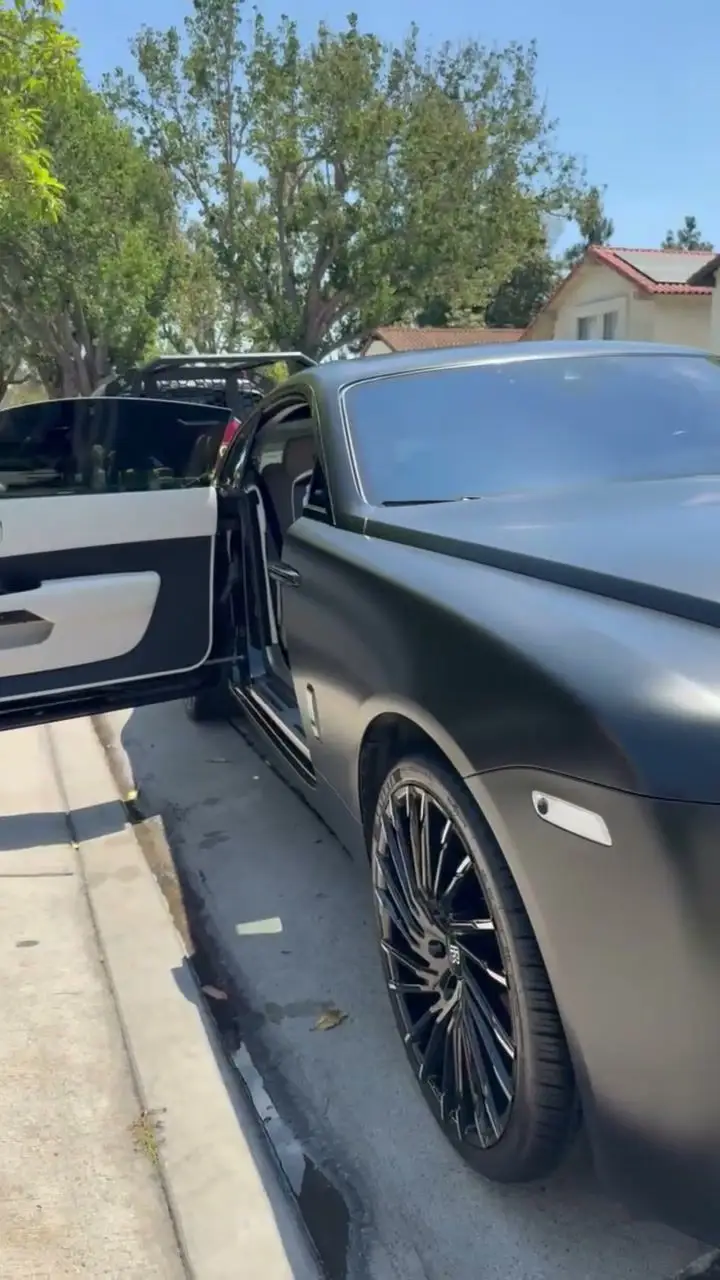 Matte black Rolls-Royce Wraith at the curb with the driver door open