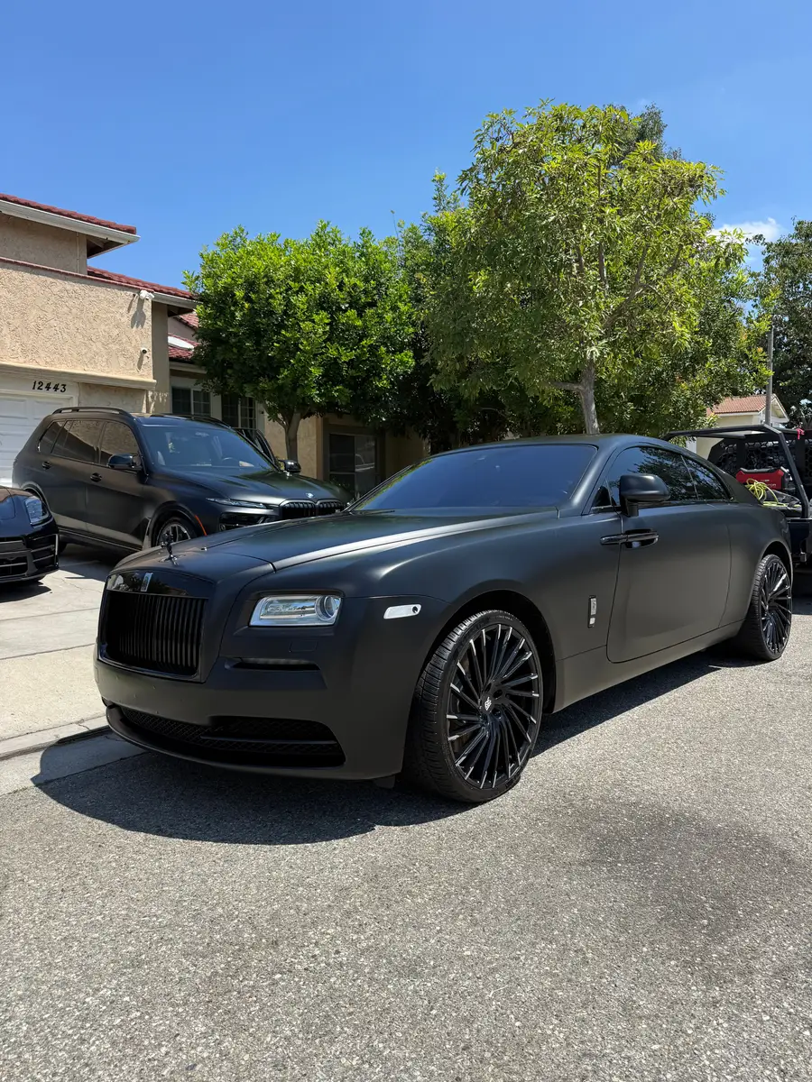 Matte black Rolls-Royce Wraith after a detail, parked on a residential street
